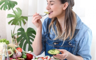 Young and happy woman eating salad at the table